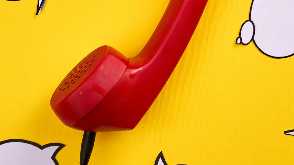 Cornetta del telefono rossa su sfondo giallo